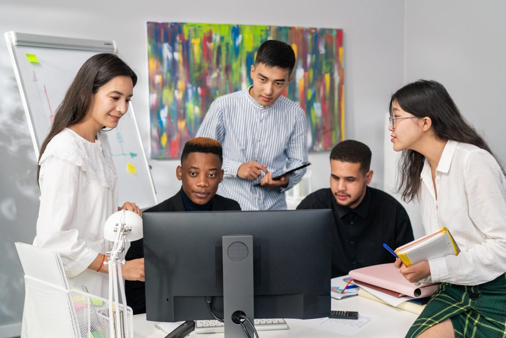 Five employees of corporation spend morning working hard on new project, they stare at computer monitor, take notes, collaboration, company atmosphere, successful people, business, brainstorming
