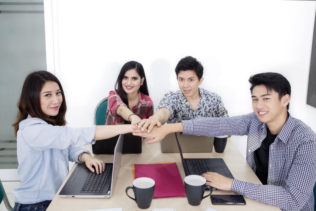Young freelancer team join hands after a meeting