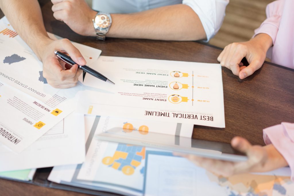 Close up of businessman reading reports and discussing them with female colleague