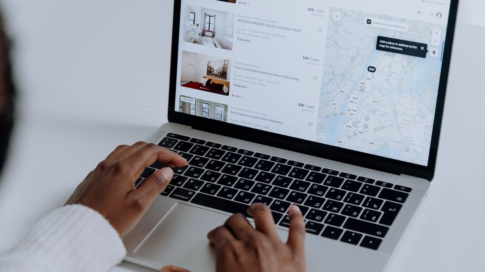 Hands on a laptop browsing a marketplace's listings page with a map of vendor offers and prices