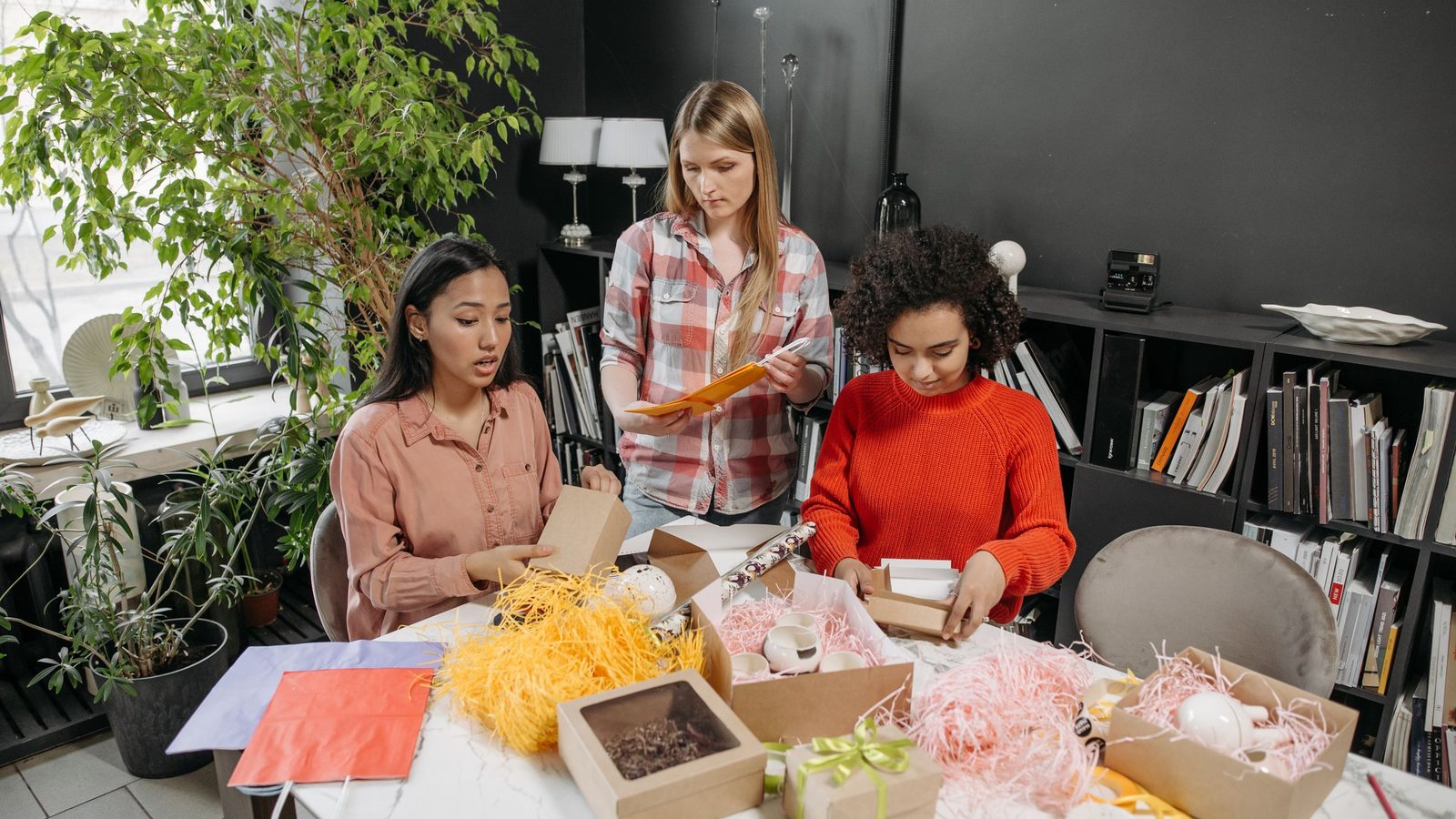D2C brand team packing gift boxes of products at a table in their office studio