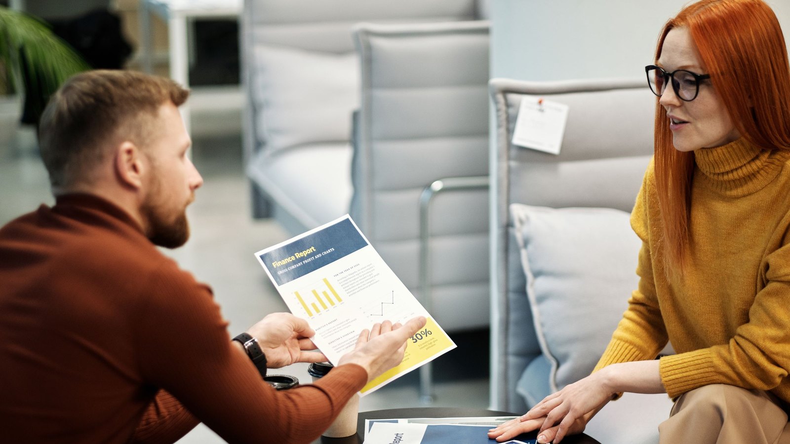 Founder and ops lead discussing a printed platform report across a small meeting table