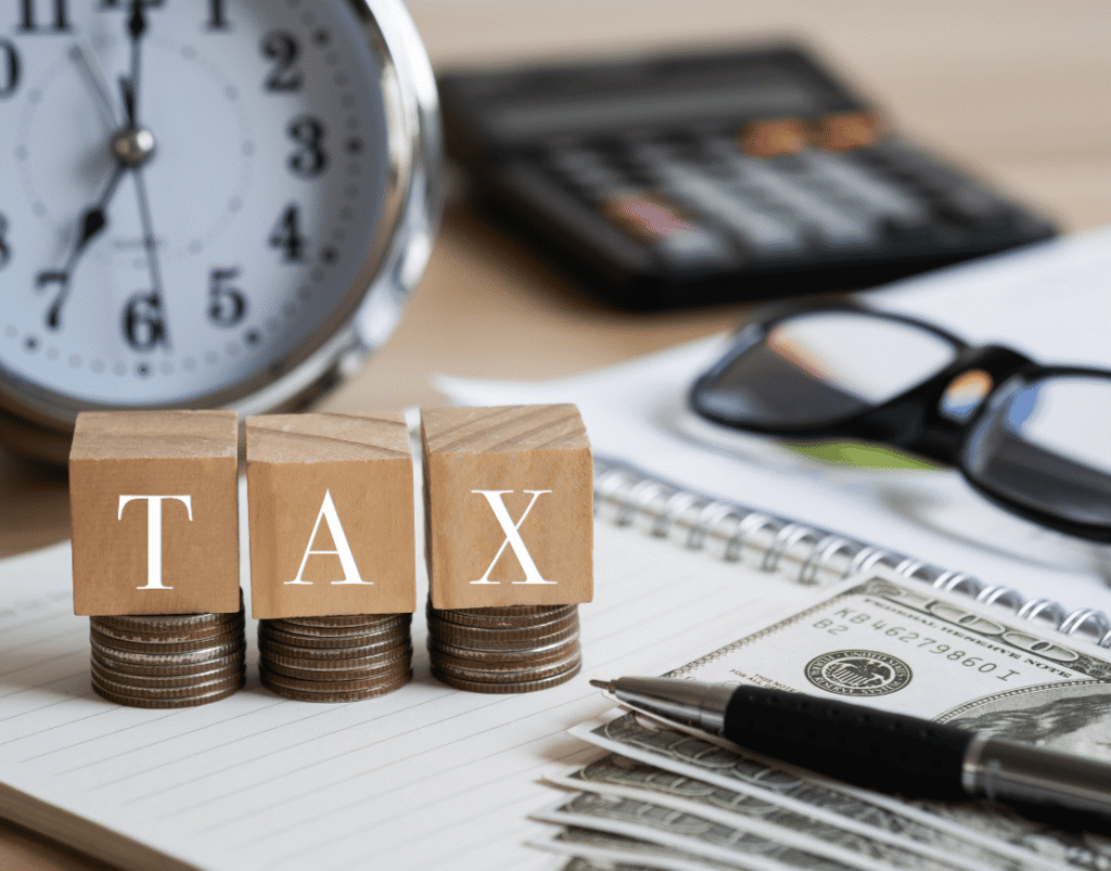 Wooden blocks spelling tax beside coins and a calculator, the tax reporting behind e invoicing UAE requirements