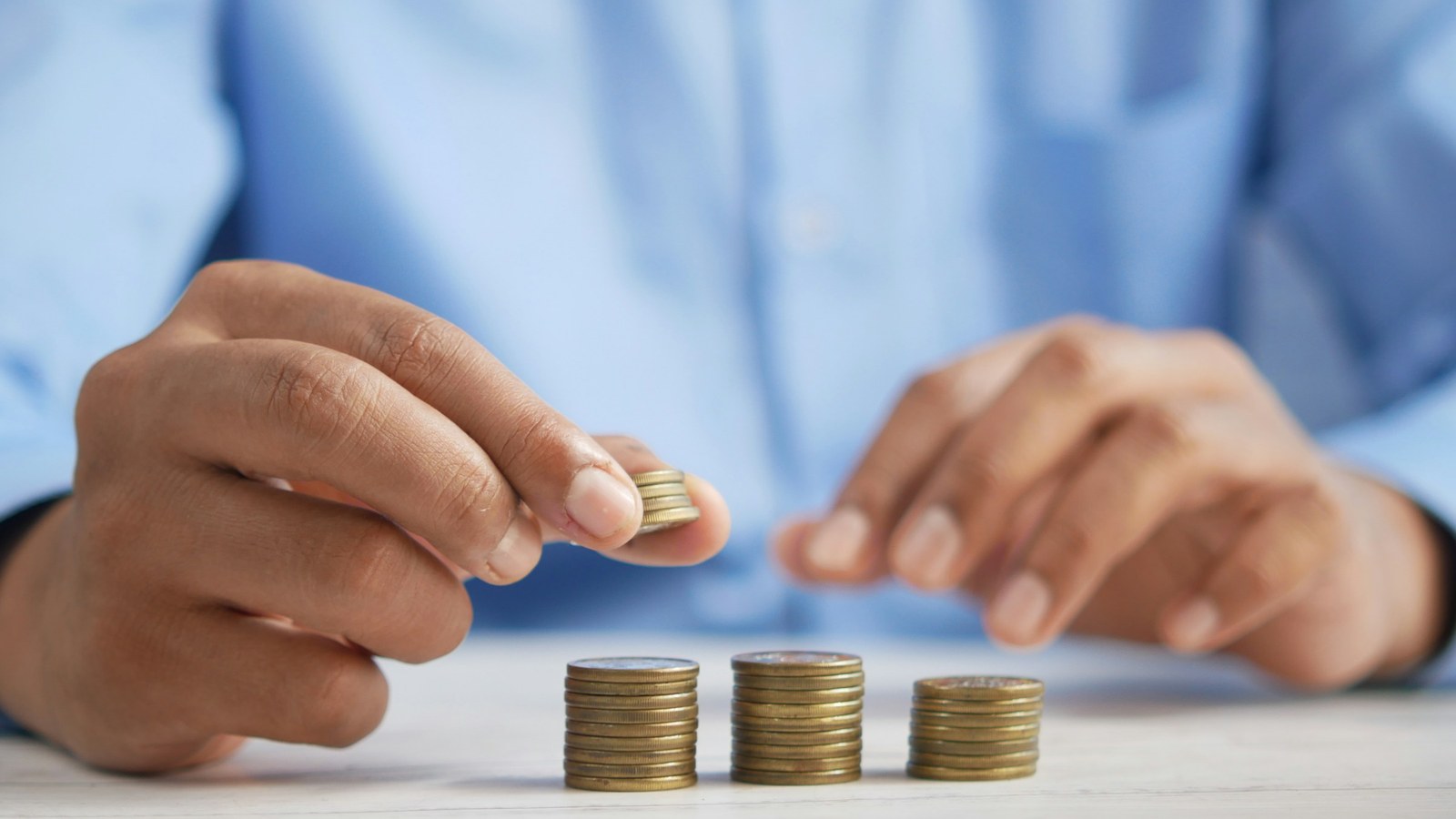 Hands stacking coins on a desk, illustrating marketplace commission and payout money logic