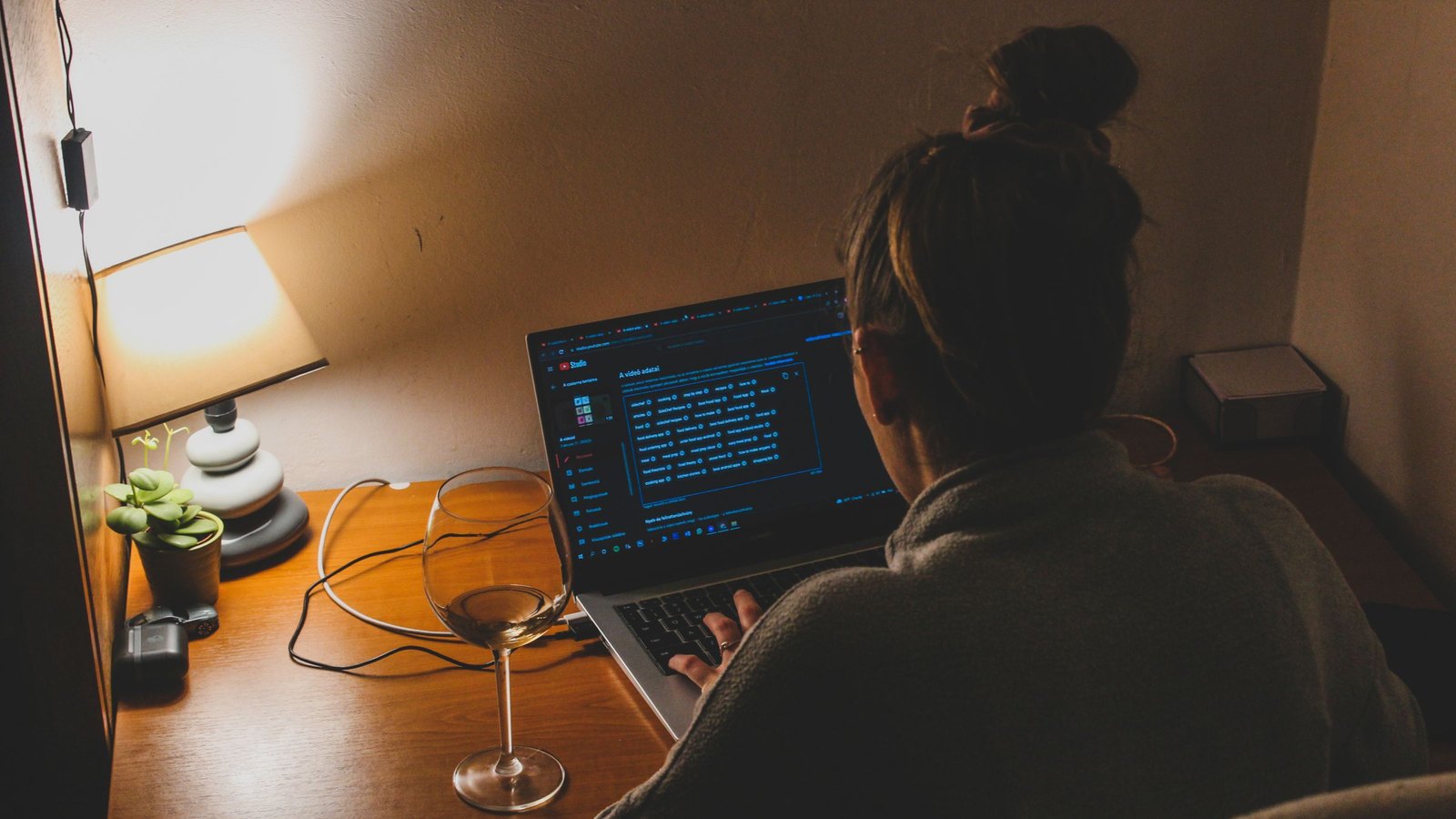 Founder working late on a laptop in a dim room, lit only by a desk lamp