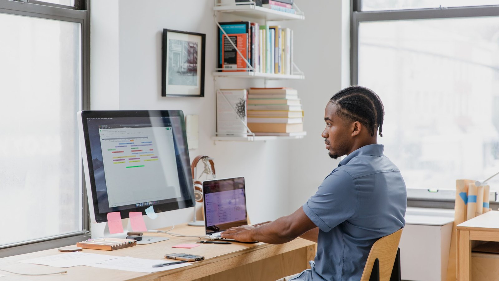 Ops staffer working across a desktop monitor and a laptop while planning a store data migration