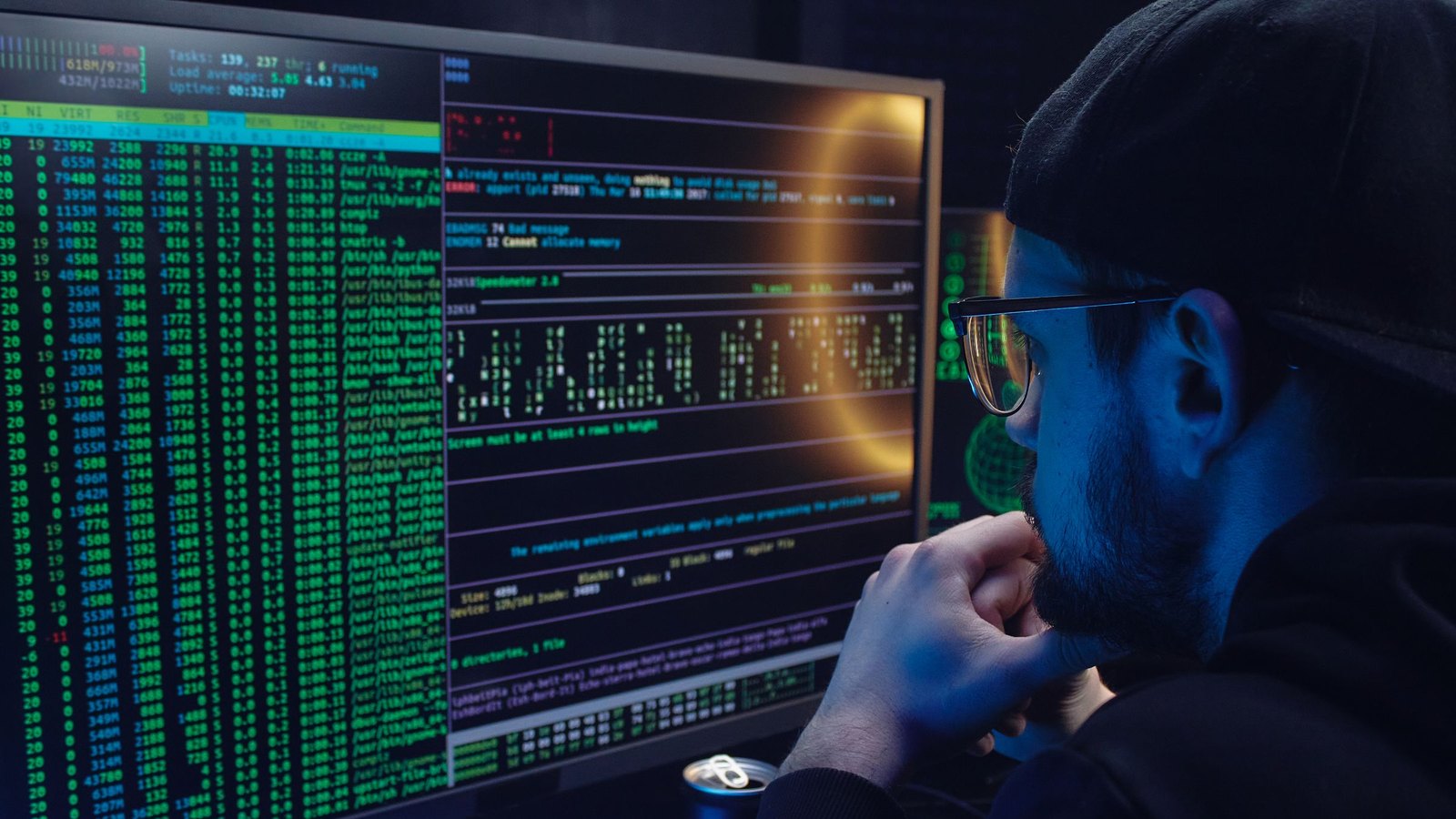 On-call developer watching a server monitor showing load average, uptime, running processes and memory errors