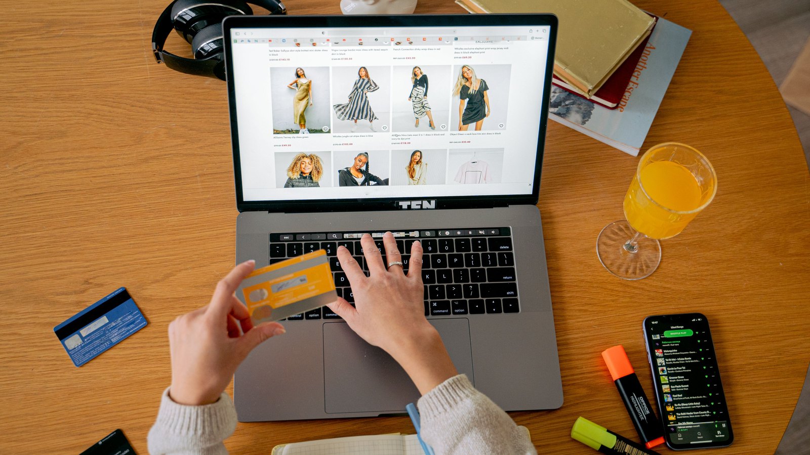 Shopper paying by card on a laptop storefront, phone at hand for the 3-D Secure step that can stall an order