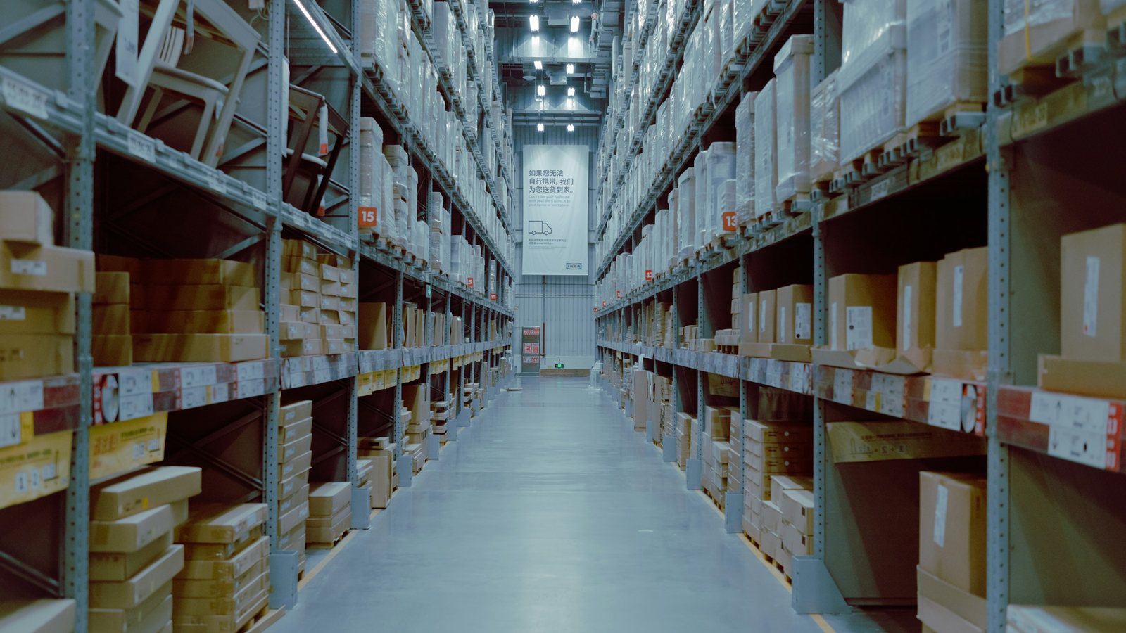 Long distributor warehouse aisle with high shelving full of boxed parts, showing a large and complex catalogue