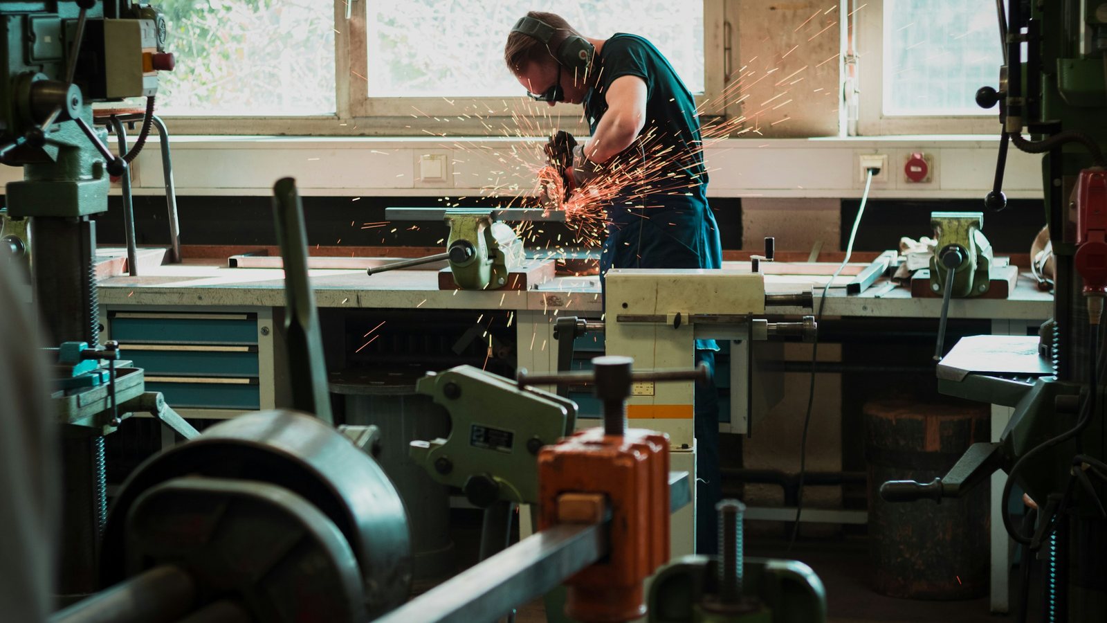 Worker cutting metal with an angle grinder on a factory floor, the kind of manufacturer that moves ordering online