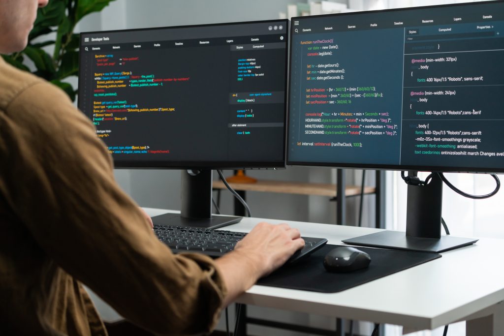 IT developer working online software development coding on pc screens. Gusher.