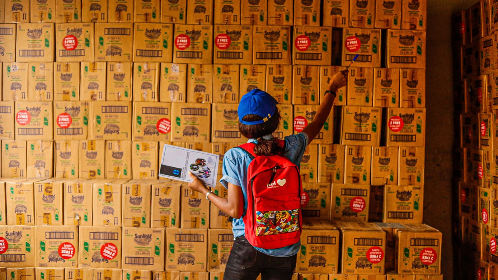 Warehouse worker counting stacked cartons against a checklist, where tier breaks that ignore pack sizes cause picking errors