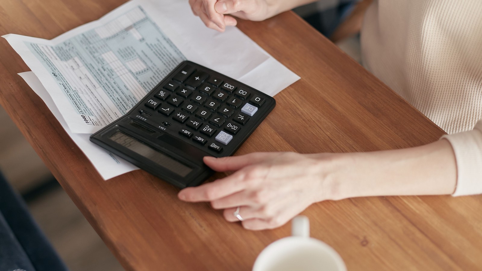 Hands working through printed figures with a desk calculator, the margin check behind each tier design trade-off